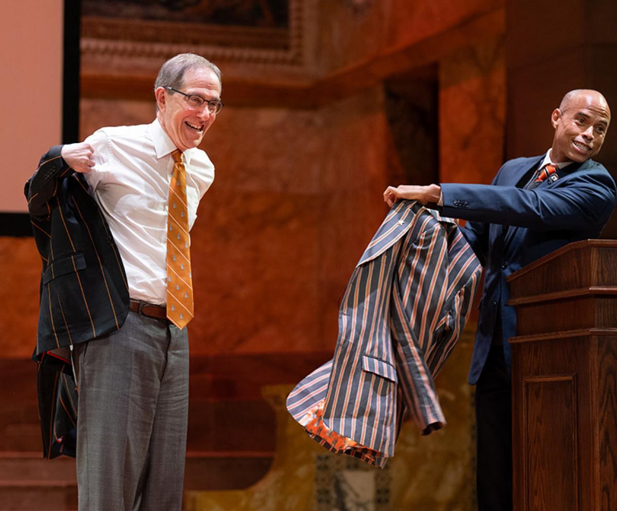 Christopher Eisgruber grins while he tries on his new APGA blazer, a gift from Laurence Latimer.