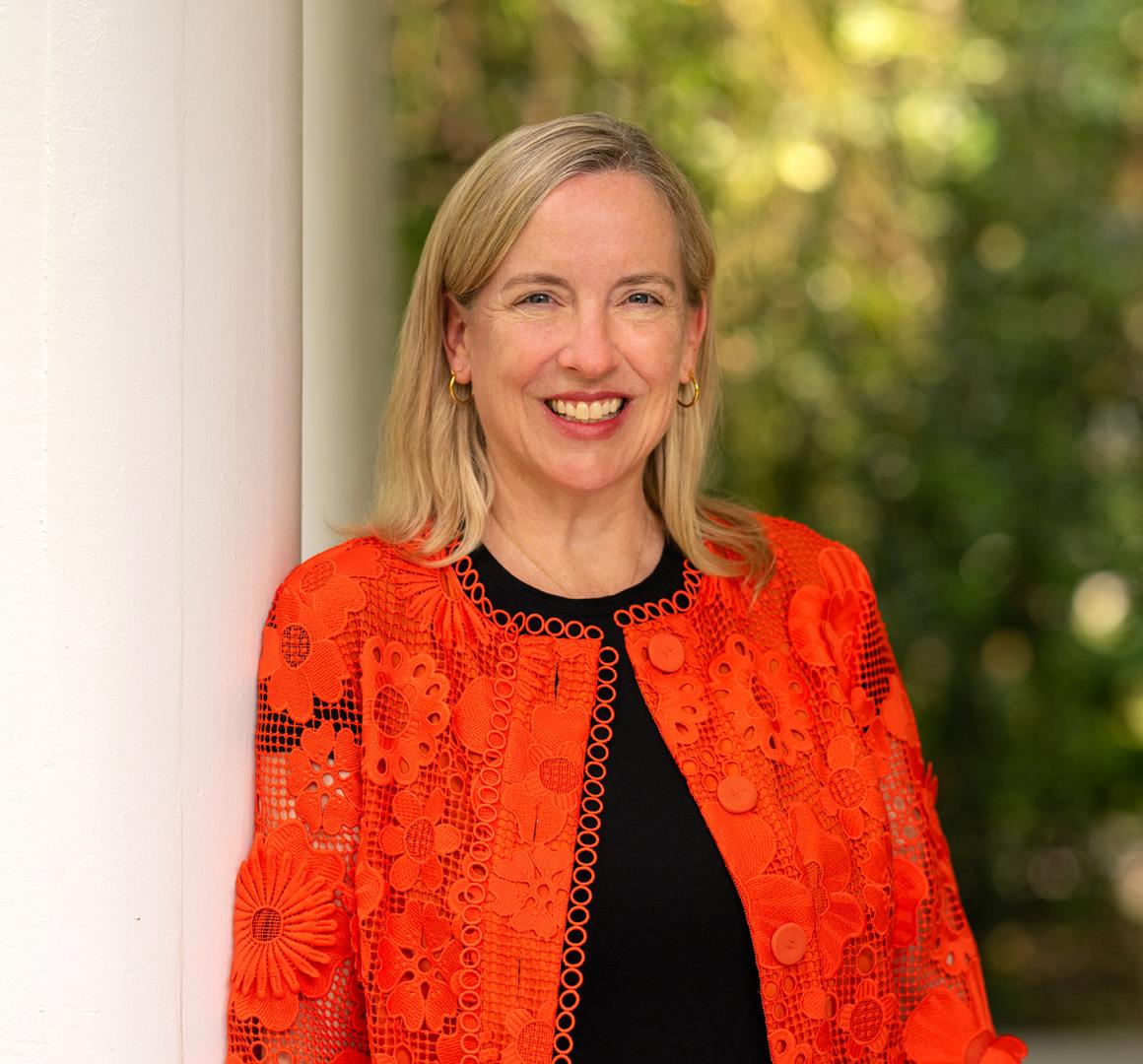 Profile of Jen Caputo, wearing an orange sweater