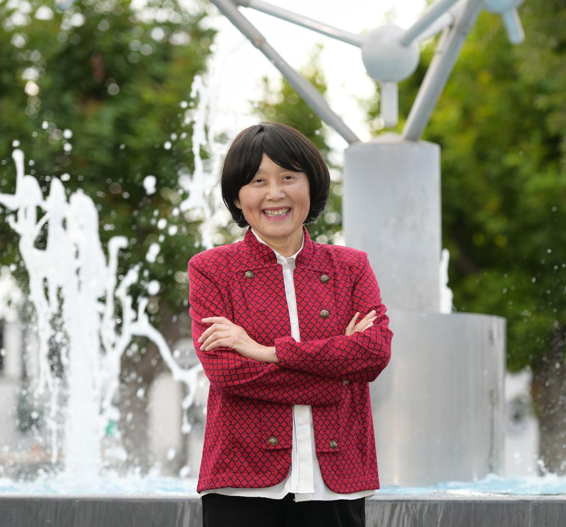 Mary Luo, dressed in red, smiling in front of a fountain