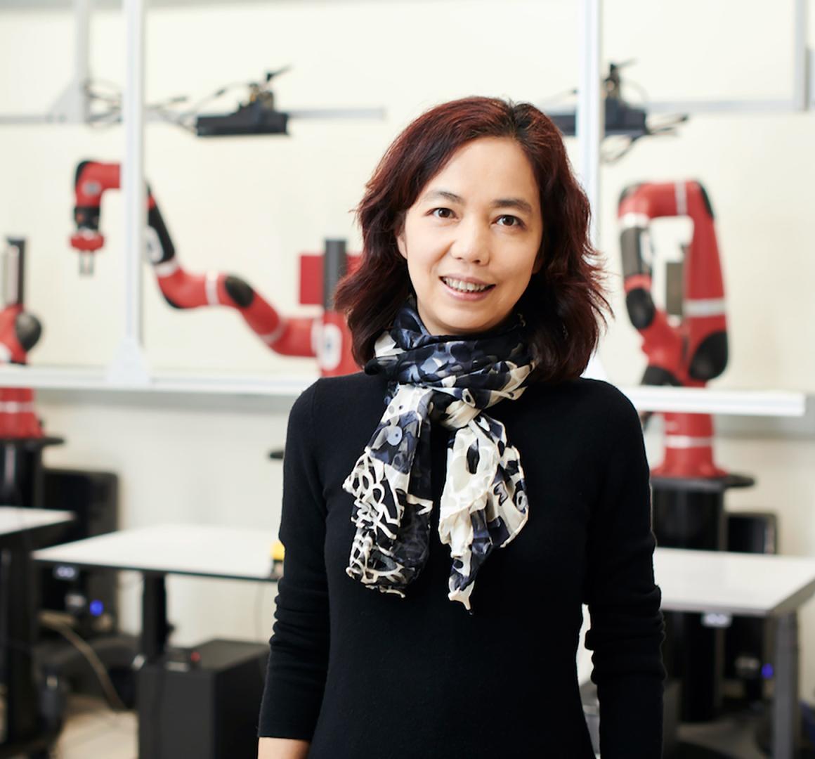 Fei-Fei Li, posing for the camera in a robotics lab