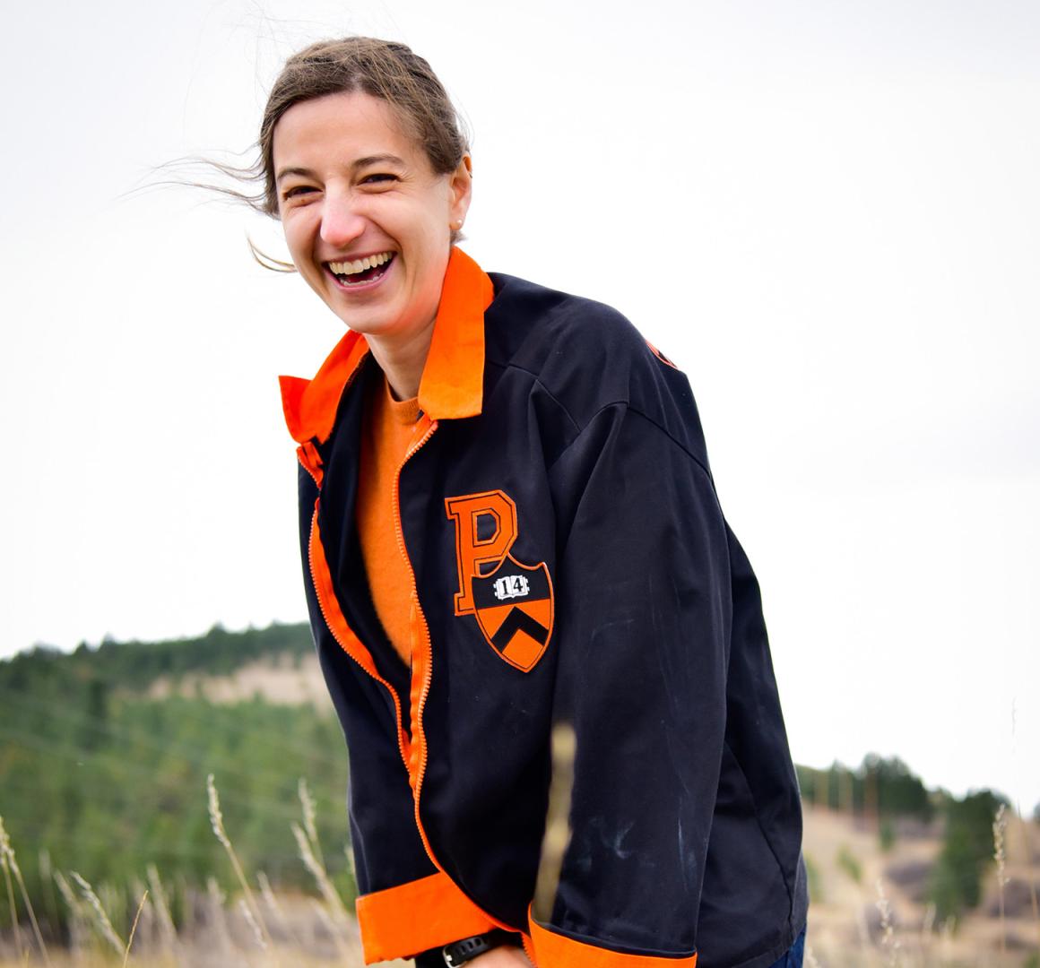 Maura Whelan, wearing her Princeton Reunions jacket, standing in a windy field and smiling