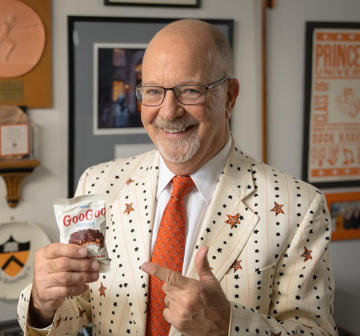 Frederick Strobel in his office, smiling while he holds a bag of candy snacks