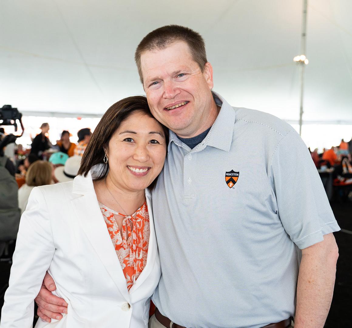Doug and Susan Massick, arm in arm, under a tent at Reunions in 2023