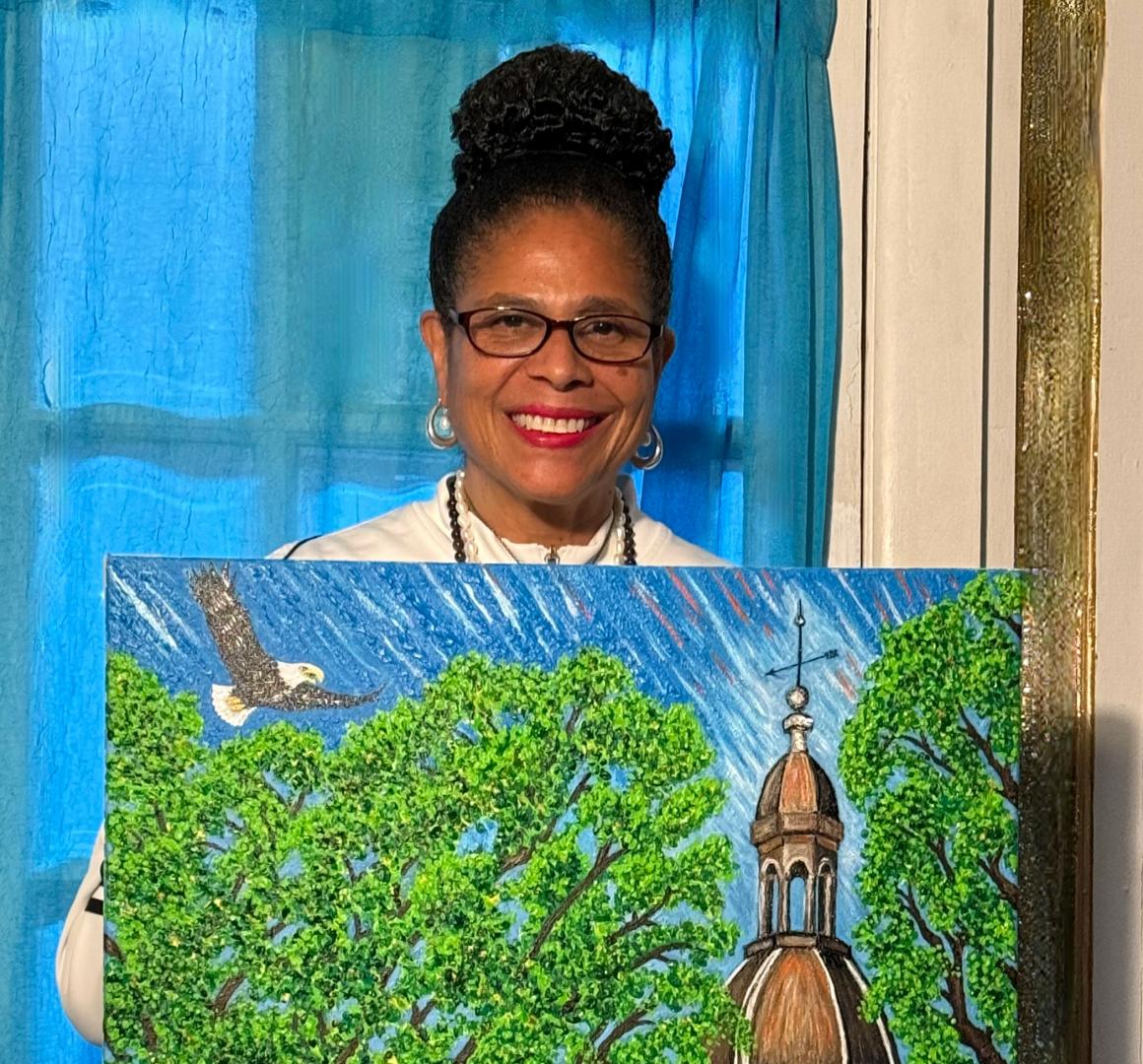 Barbara Wallace holding her painting of Nassau Hall that was used on the Reunions 2025 program