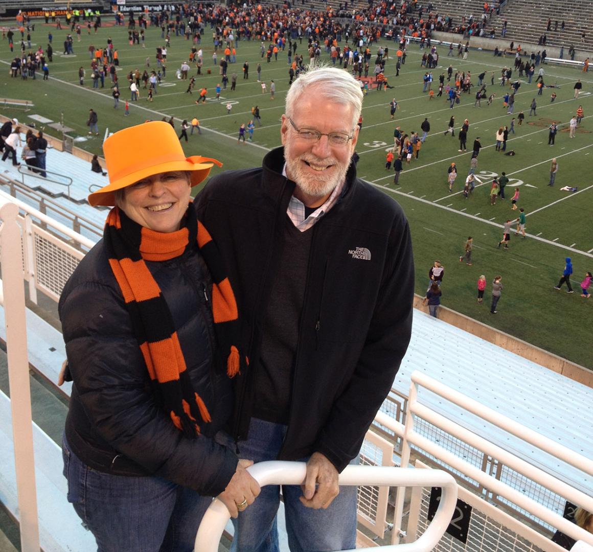 Bonnie Hewson and Chuck Marboe with a football stadium field in the background
