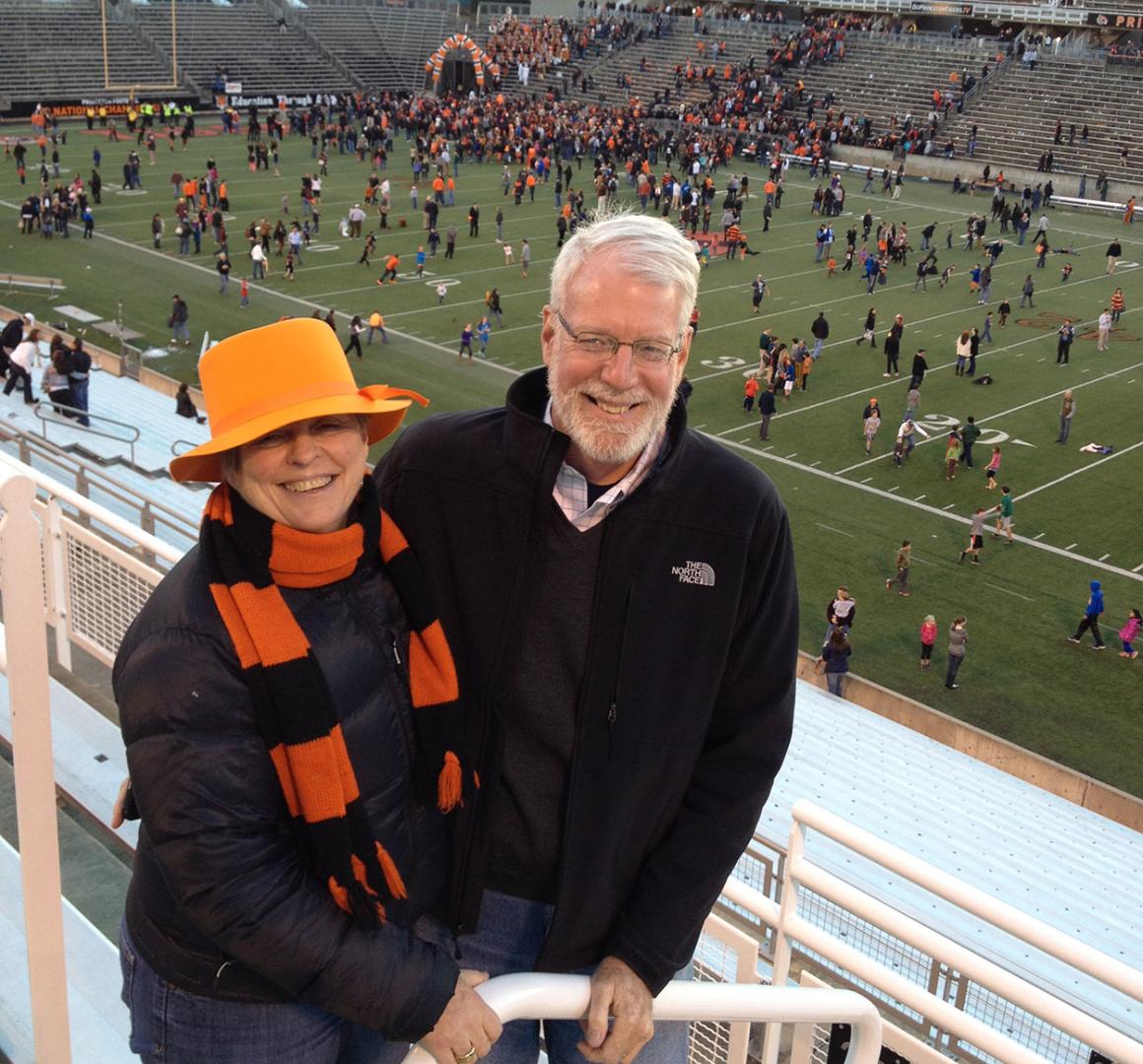 Bonnie Hewson and Chuck Marboe with a football stadium field in the background