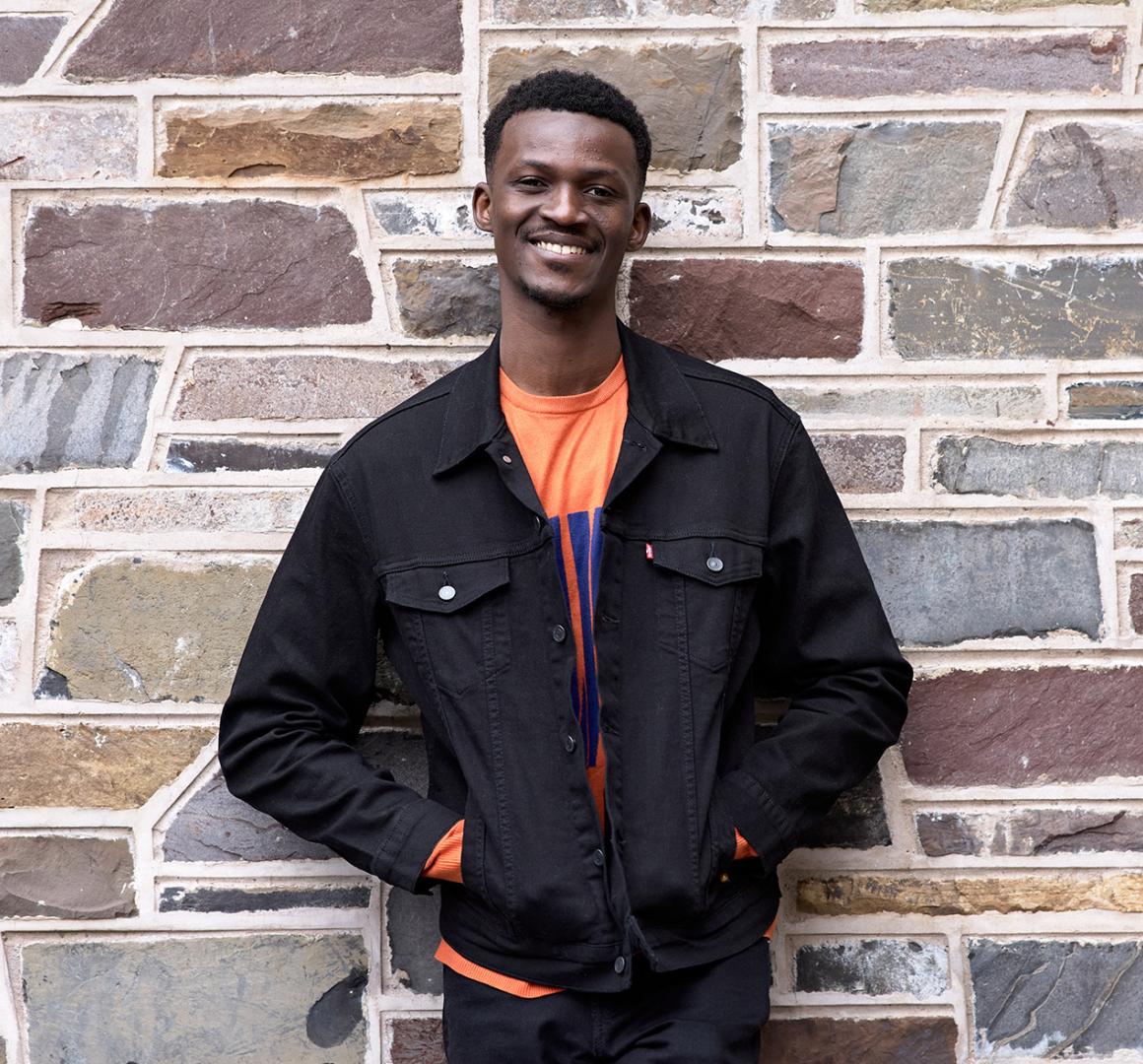 Godwin Obi, smiling and standing in front of stone exterior of academic building. 