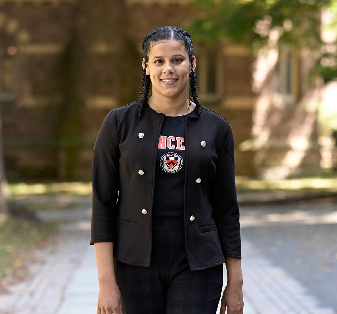 A smiling Princeton student walking near Nassau Hall. 