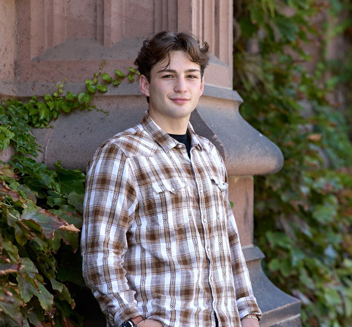A Princeton student leaning against an Ivy-covered exterior.