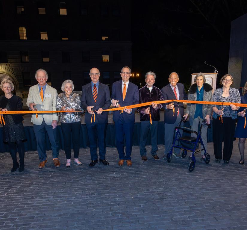 University officials and alumni hold and cut an orange ribbon to dedicate the new Art Museum.