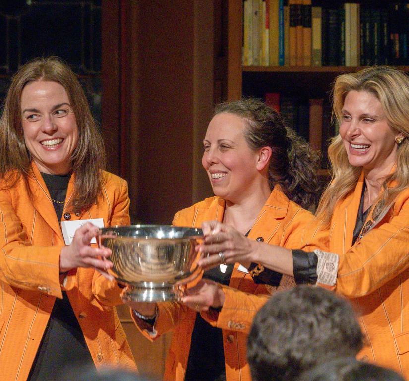 Wearing identical orange jackets, Tiffany Madigan, Stephanie Ramos and Alexis Moses proudly hold the Class of 1926 Trophy.
