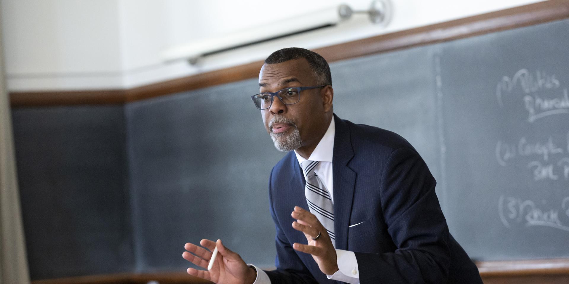 Professor Edie Glaude Jr. gestures in front of chalkboard