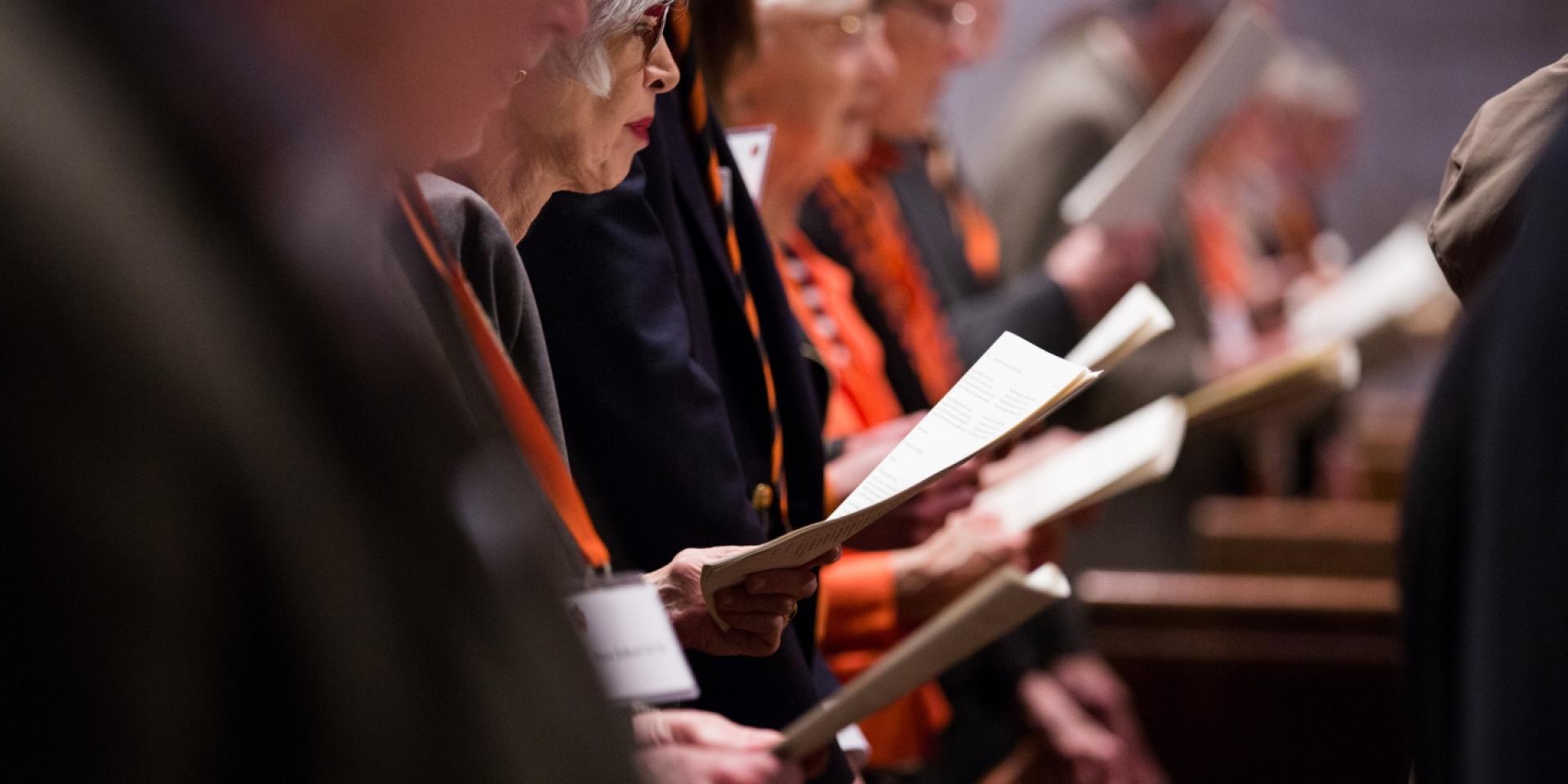 Alumni in pew holding programs or prayer books.