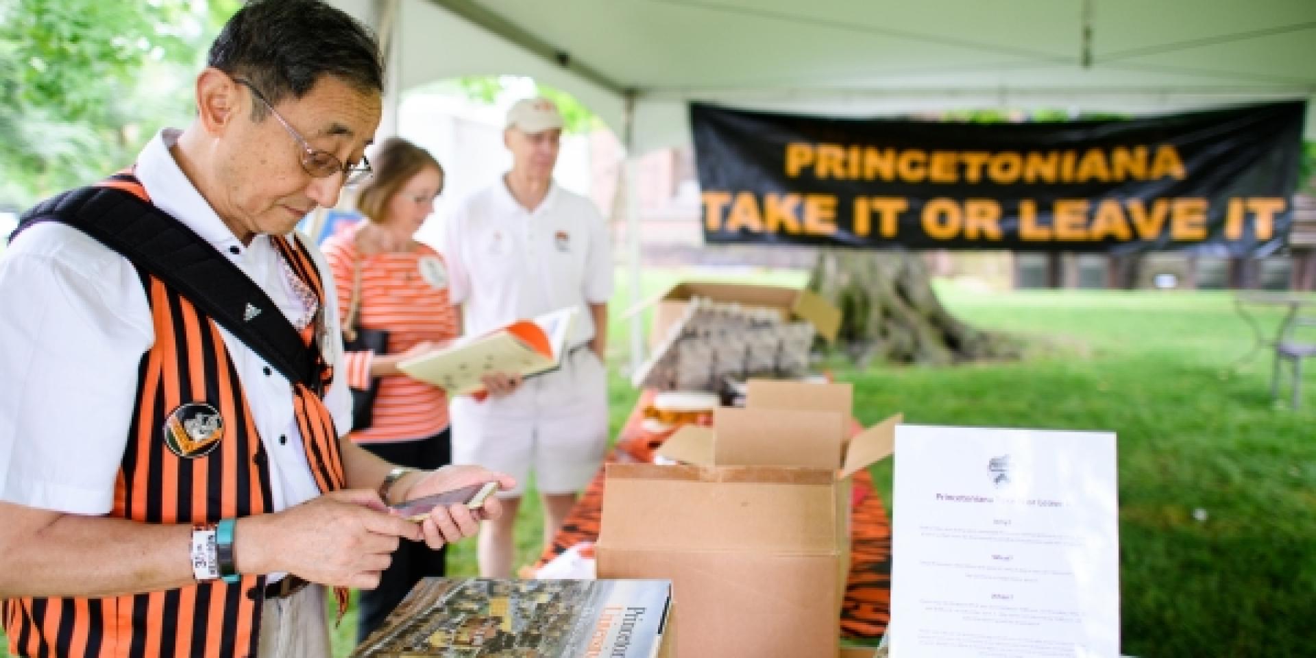 Alumnus perusing the Take it or Leave it tent for memorabilia