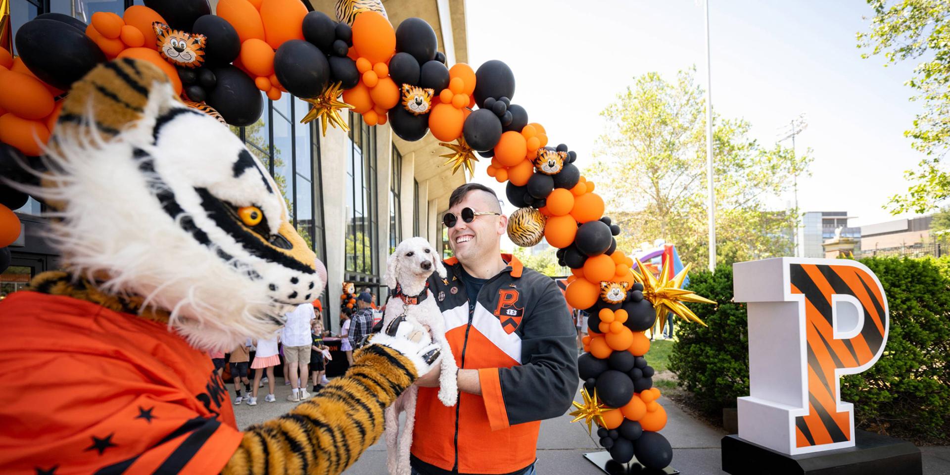 The Tiger mascot great an alumni, who is holding his dog, during Reunions