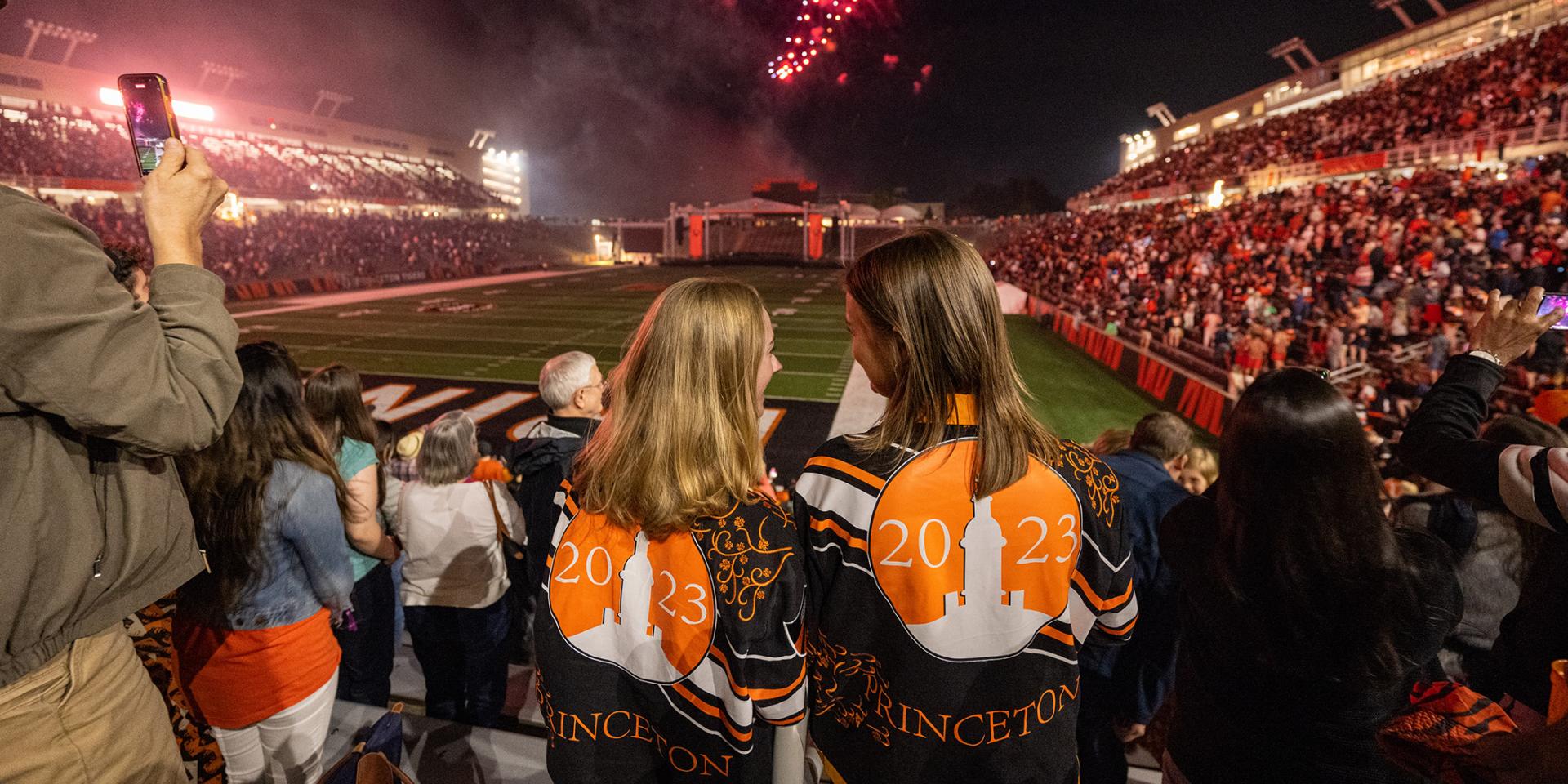 Two female alumni watch the Reunions fireworks in Princeton Stadium.