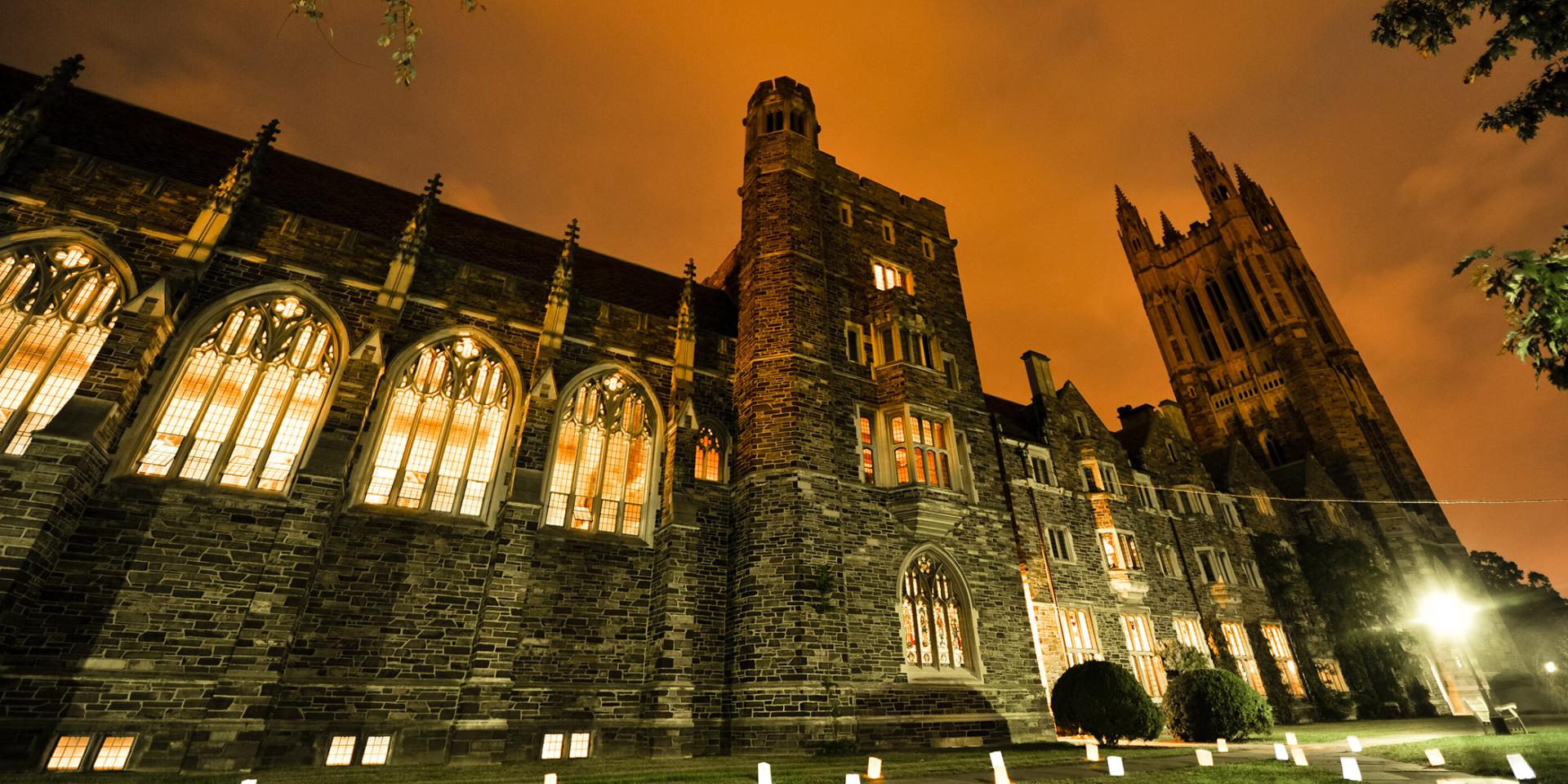 The Princeton Graduate College, lit up in orange light at dusk during the 2016 Many Minds Many Stripes alumni conference
