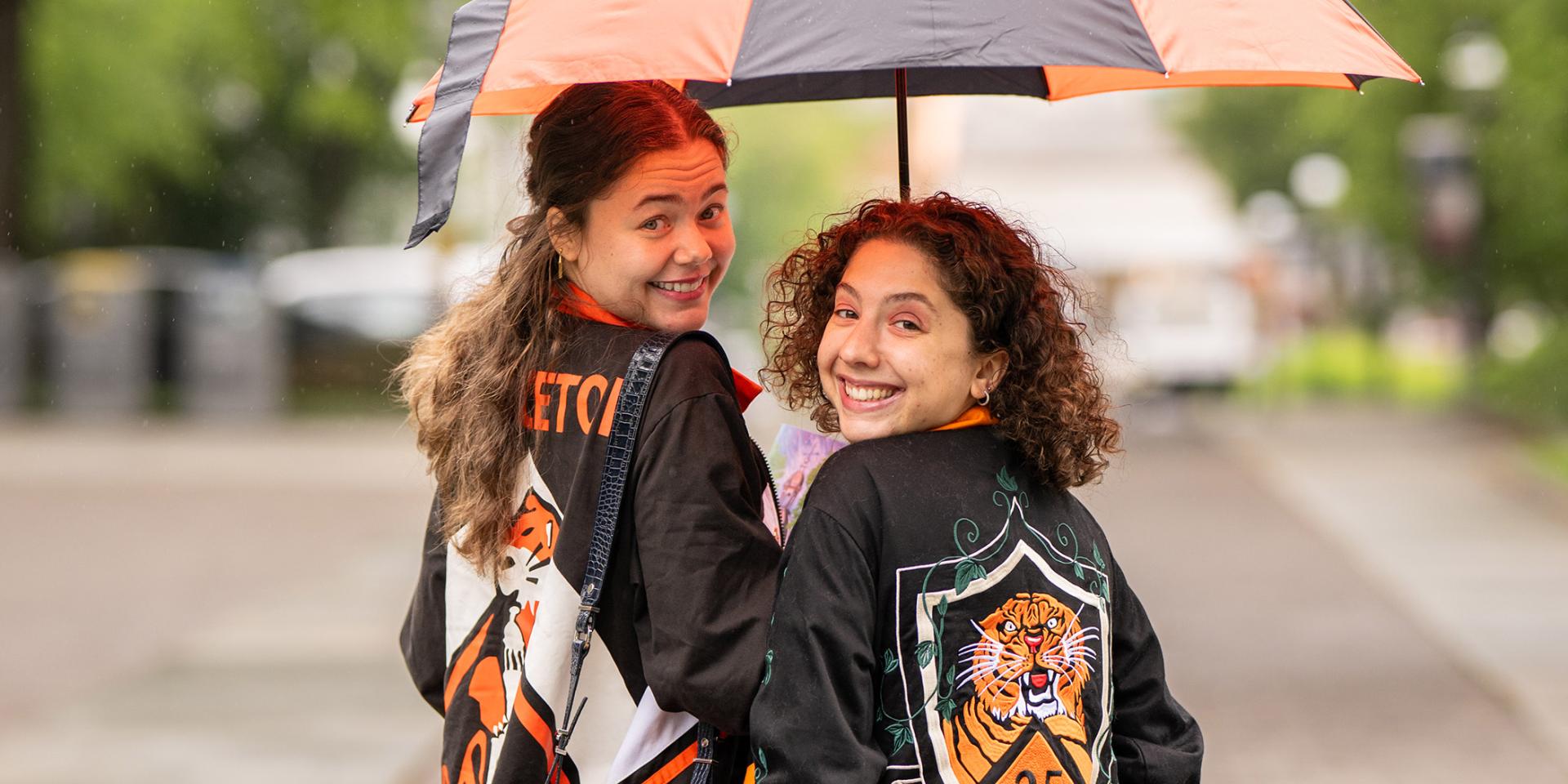 Two Princeton alumnae under an orange and black umbrella