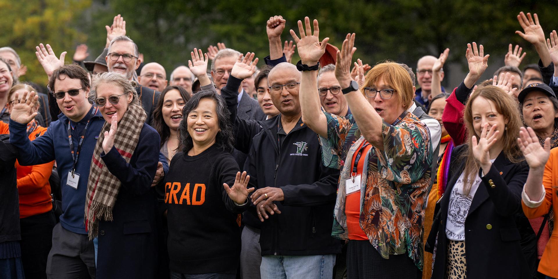 Alumni of the Graduate School woot and holler on Poe Field before a group photo during the Many Minds conference.