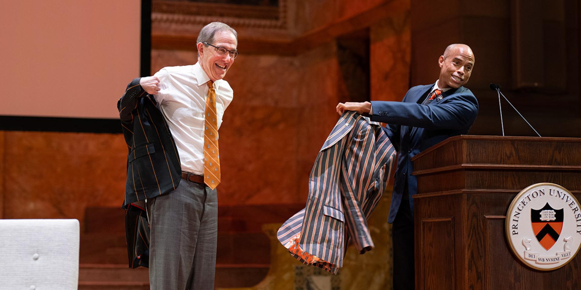 Christopher Eisgruber grins while he tries on his new APGA blazer, a gift from Laurence Latimer.