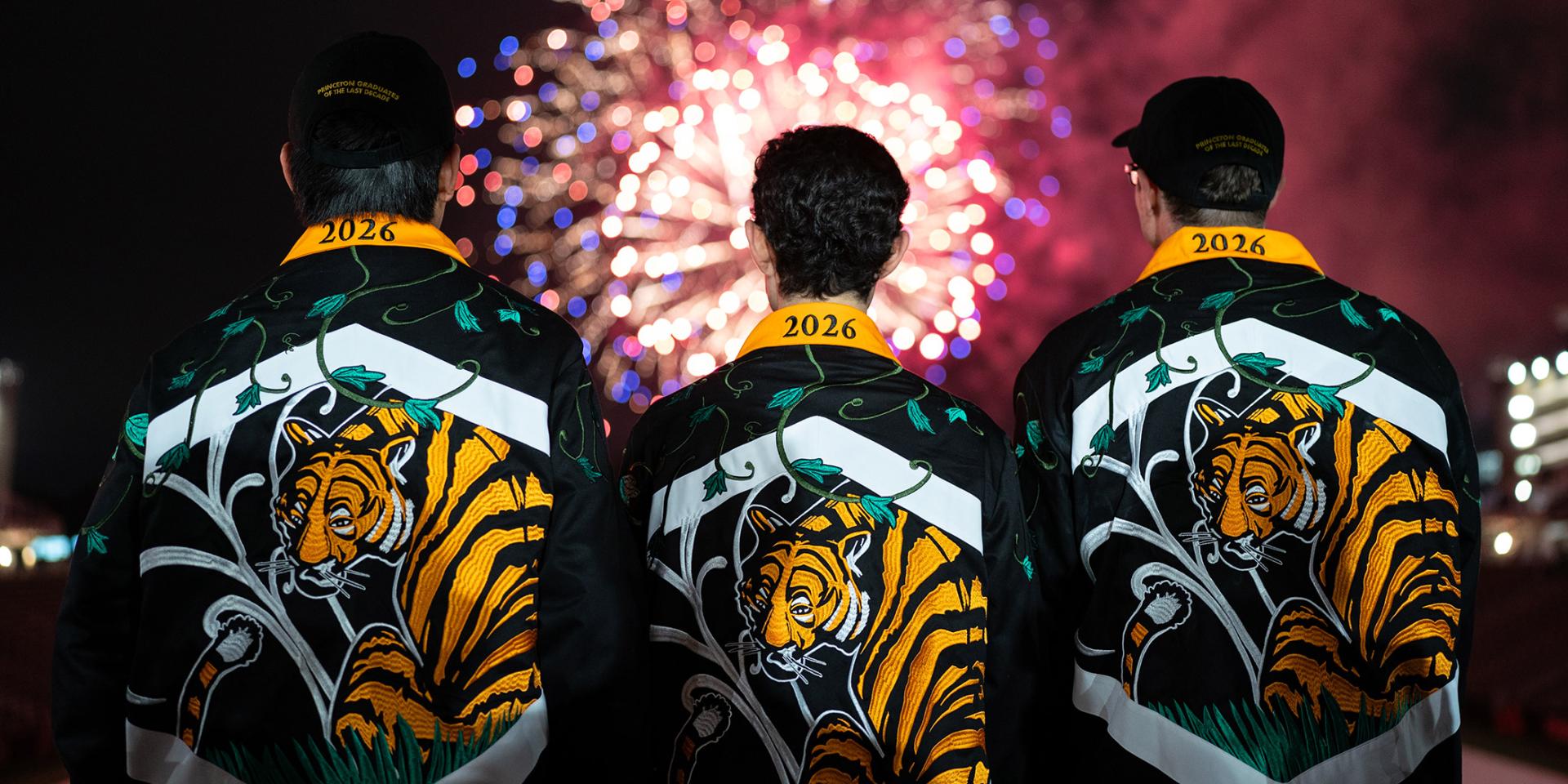 Three members of the Class of 2026 watch the Reunions fireworks in Princeton Stadium