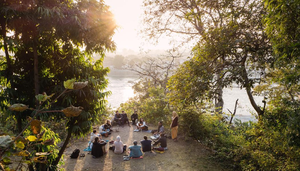 A group sits in a circle by a river
