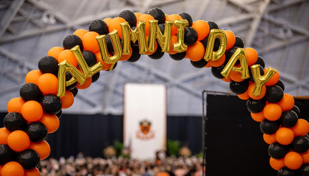 Orange and black balloon arch with balloon letters that say Alumni Day