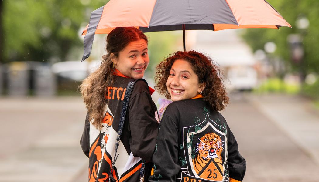 Two Princeton alumnae under an orange and black umbrella