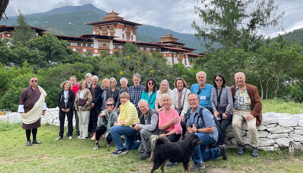 Kathy and Fred Miller with a group of fellow travelers outdoors in front of a building and mountain in Bhutan