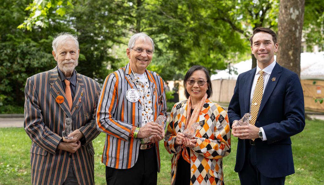 Three men and one woman stand outside holding crystal tigers