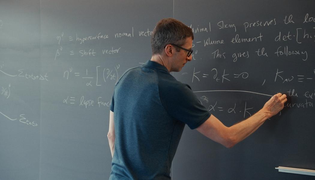 A male professor calculates advanced math equations on a classroom chalkboard.