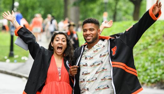 Two young alumni with arms in air in celebratory fashion.