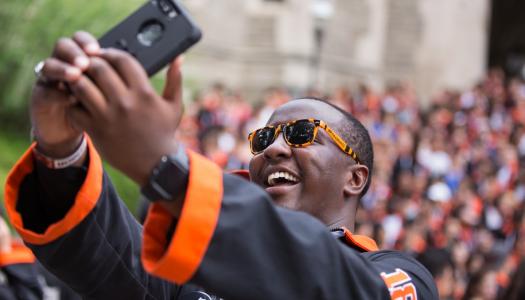 Young alumnus taking selfie with graduated class.