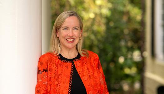 Profile of Jen Caputo, wearing an orange sweater