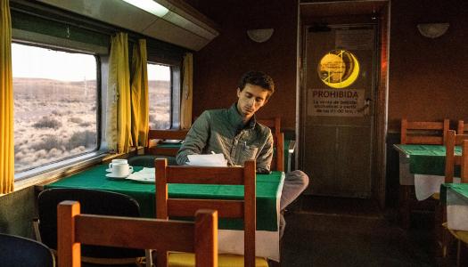 Jordan Salama writing in his notebook aboard a train