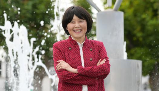 Mary Luo, dressed in red, smiling in front of a fountain