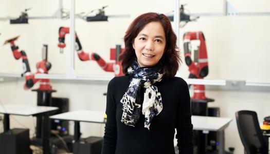 Fei-Fei Li, posing for the camera in a robotics lab