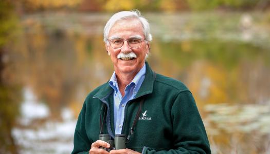 John Fitzpatrick, in nature, holding binoculars