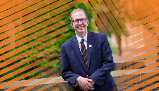 Andrew Houck smiling, dressed in blazer and tie.