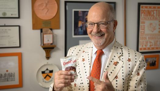 Frederick Strobel in his office, smiling while he holds a bag of candy snacks