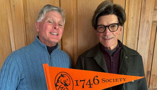 Guy Lawrence and his husband, holding an orange Princeton pennant
