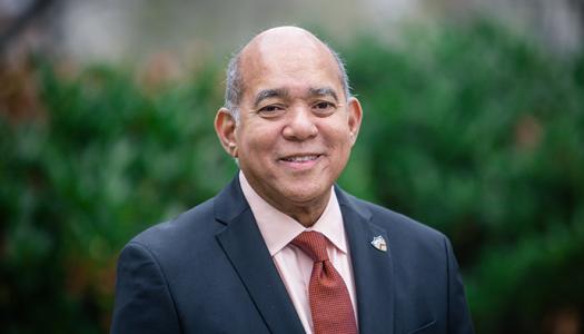 Mozell Thompson wearing a blue suit and orange tie