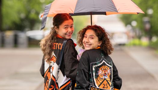 Two Princeton alumnae under an orange and black umbrella