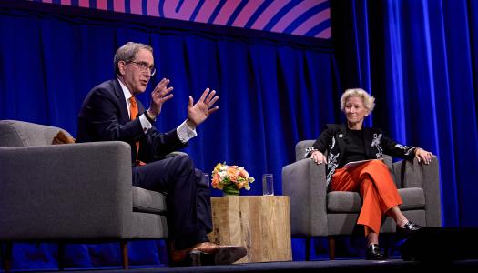 President Eisgruber, seated on stage alongside Weezie Sams, speaking to a packed hall.