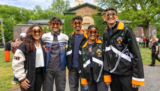 Five younger alumni wearing special 200 anniversary sunglasses while standing in front of Nassau Hall