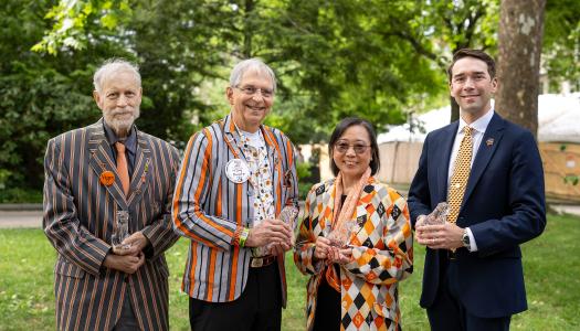 Three men and one woman stand outside holding crystal tigers