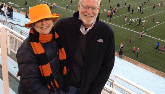 Bonnie Hewson and Chuck Marboe with a football stadium field in the background
