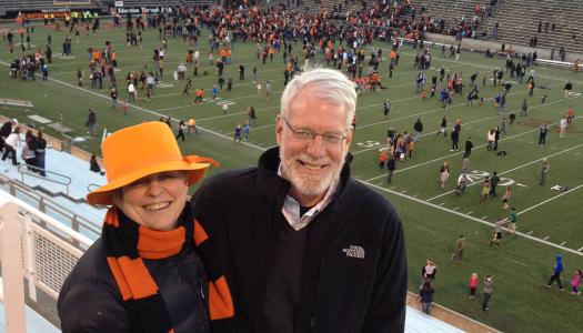 Bonnie Hewson and Chuck Marboe with a football stadium field in the background