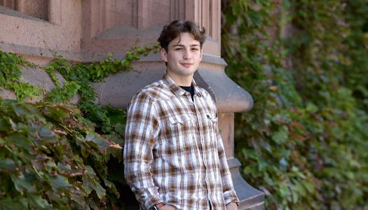 A Princeton student leaning against an Ivy-covered exterior.