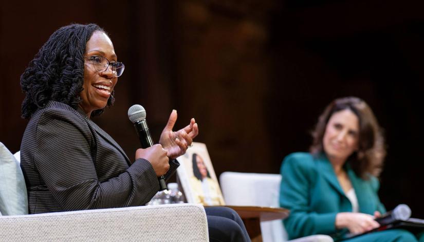 Justice Jackson, on stage, speaking to the audience while holding a microphone.